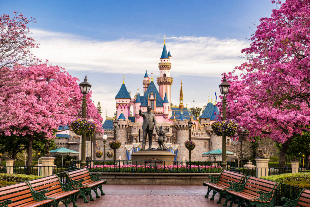 Disneyland Resort - Walt Disney and Mickey Mouse holding hands in front of the castle. Learn how to become a travel agent today.