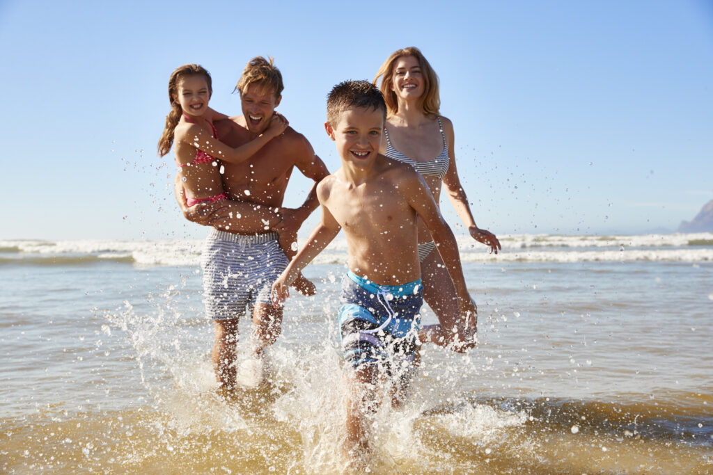 Best travel agency to work for - family splashing in the ocean waves